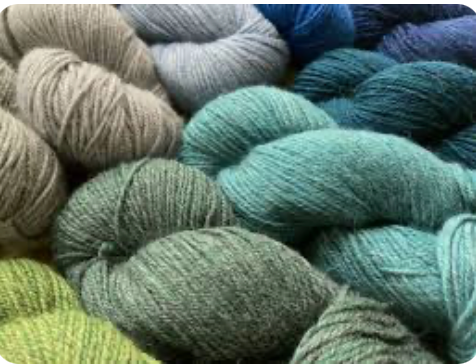 Collection of yarn skeins in various shades of green and blue.